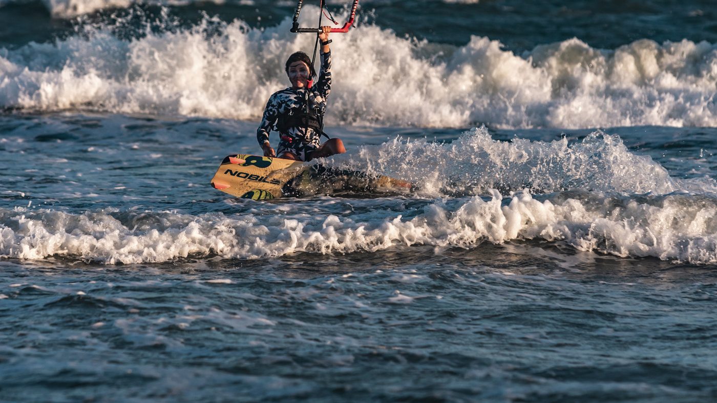 A rider up on the board and riding out through broken water.