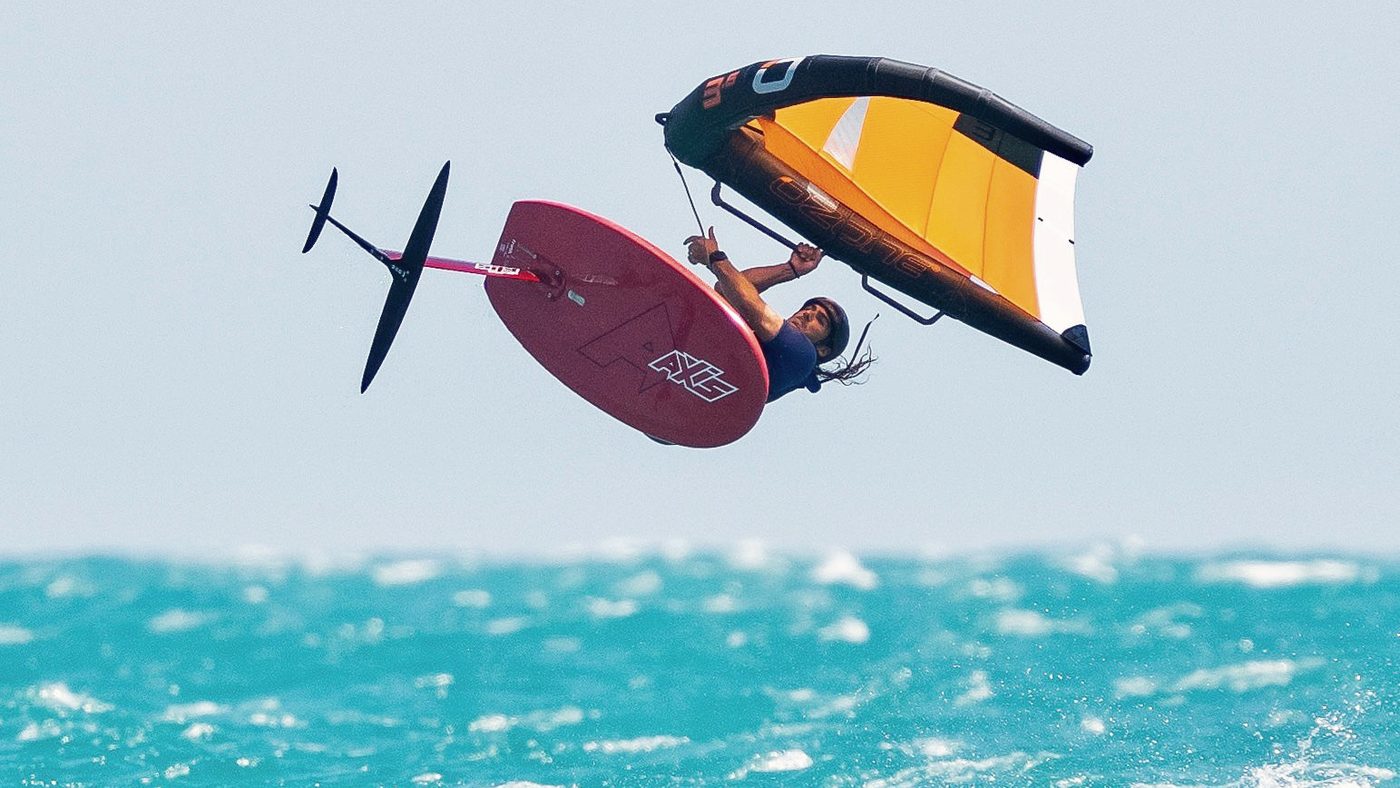 A wingfoiler clear of the water, board and foil lifted, wing held overhead off Mui Ne.