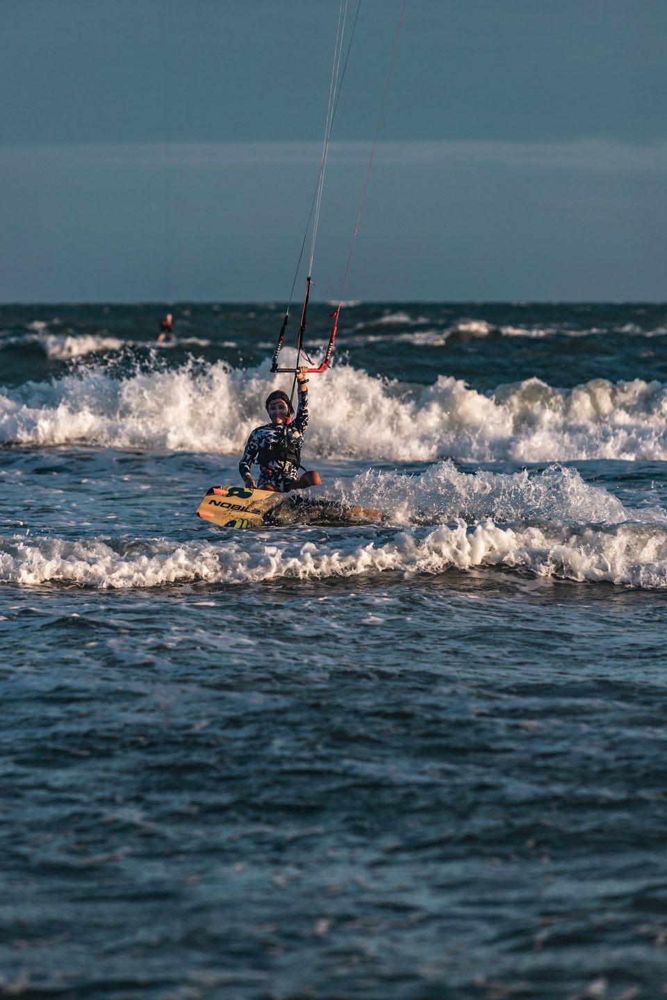 A rider up on the board and riding out through broken water at Mui Ne, kite low and forward.