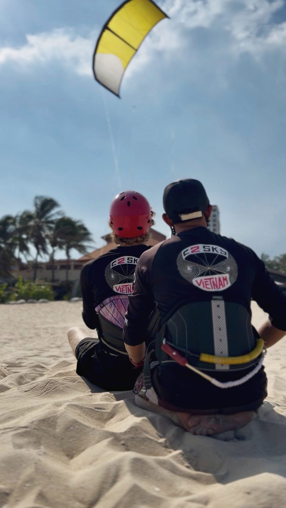 A C2SKY instructor and a student sitting together on the sand, going through the session before it starts.