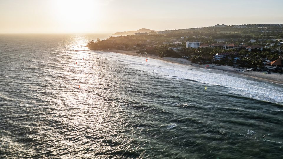 The Mui Ne coastline at sunset from the air, the low sun laying a path across the water.