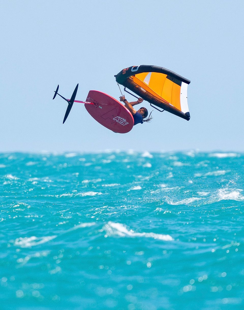 A wingfoiler riding clear of the water at Mui Ne, wing held out to the side and the foil carrying the board above the surface.