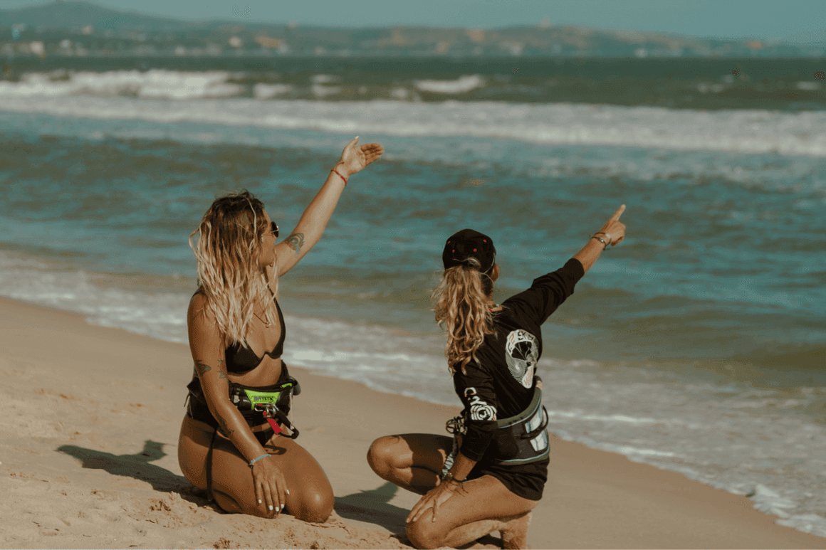 Liz, IKO head instructor at C2SKY, pointing out kite conditions on the beach in Mui Ne, explaining wind and wave patterns to a friend.